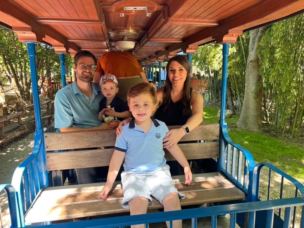 A happy family enjoying a fun day out together on the Yellow Rose train at the Fort Worth Zoo.